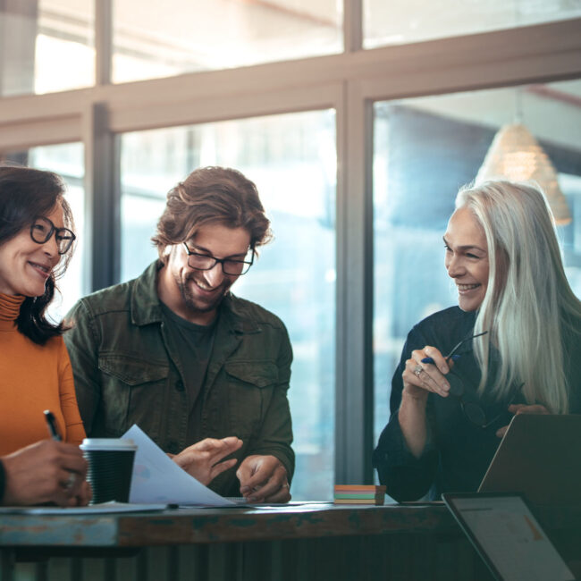 Group of business people meeting in office. Office workers standing around a table and smiling during business meeting.